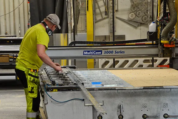 Worker in a high-visibility shirt handling a sheet on a large machine table