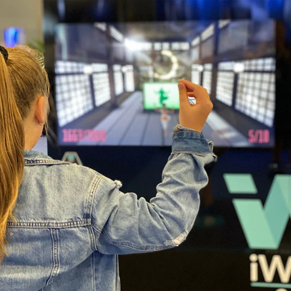 Person raising a hand in front of a large iWall game screen