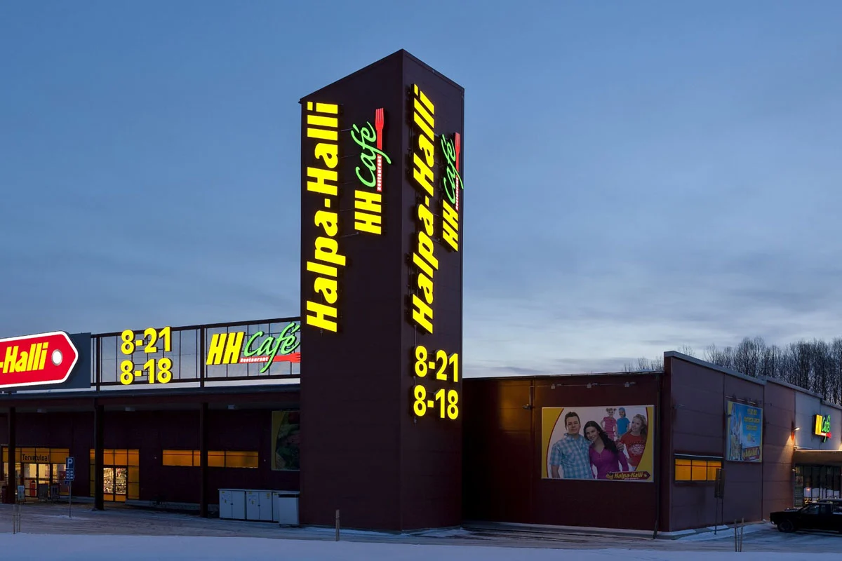 Halpa-Hallin korkea mainostorni ja keltaiset julkisivutekstit talvisessa maisemassa.