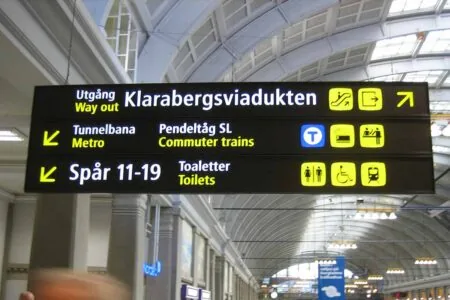 Swedish and English sign directing passengers to the exit, metro, trains, tracks 11–19 and toilets Swedish and English sign directing passengers to the exit, metro, trains, tracks 11–19 and toilets