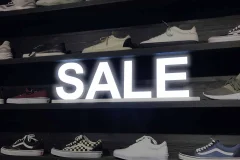 White illuminated SALE letters on a dark shoe display