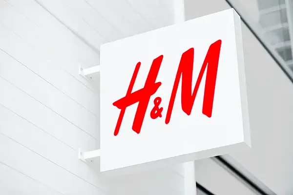 Punainen H&M-logo valkoisessa seinästä ulkonevassa neliökyltissä