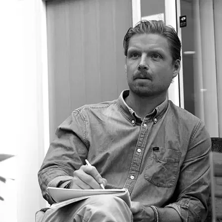 Andreas Andersson sitter med en anteckningsbok i knät och en penna i handen
