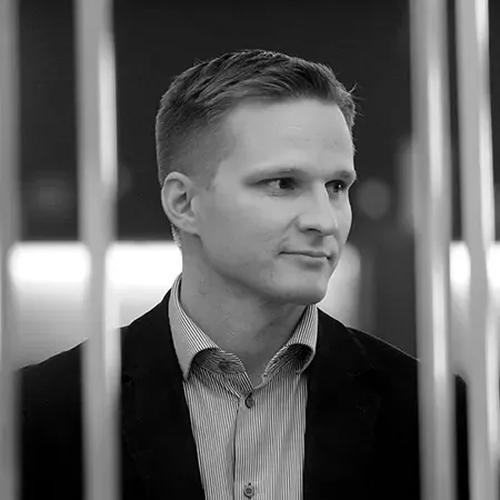 Svartvitt porträtt av Mika Okkonen i mörk kavaj och skjorta
