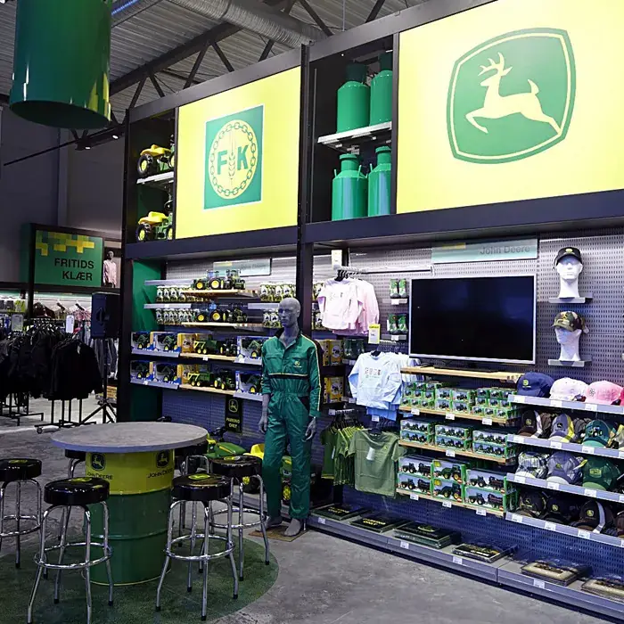 Green John Deere logos above a store wall displaying clothing and merchandise.