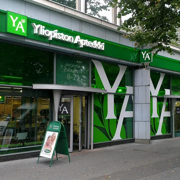 Yliopiston Apteekki's green facade sign and large YA window graphics.