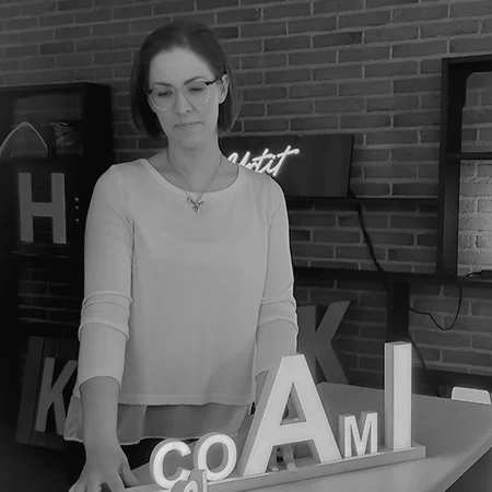 Black-and-white portrait of Anna-Reetta standing in front of display letters and a brick wall