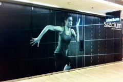 A Stadium wall graphic shows an athlete against a dark background resembling a running track. A Stadium wall graphic shows an athlete against a dark background resembling a running track.