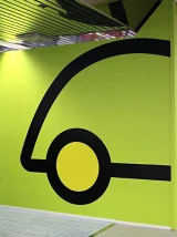 A bright green wall with a large black graphic depicting a wheeled vehicle. A bright green wall with a large black graphic depicting a wheeled vehicle.
