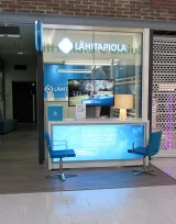 A LähiTapiola service point with a blue counter, two chairs and a display. A LähiTapiola service point with a blue counter, two chairs and a display.