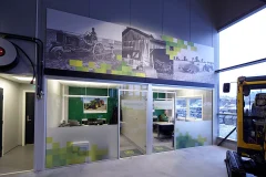 A large black-and-white historical photo collage above glass doors in a commercial space. A large black-and-white historical photo collage above glass doors in a commercial space.