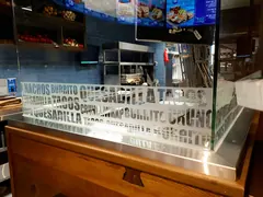 A restaurant counter's glass partition has pale lettering made up of food names. A restaurant counter's glass partition has pale lettering made up of food names.