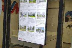 RE/MAXin asuntoilmoituksia pystysuuntaisella digitaalisella ikkunanäytöllä.