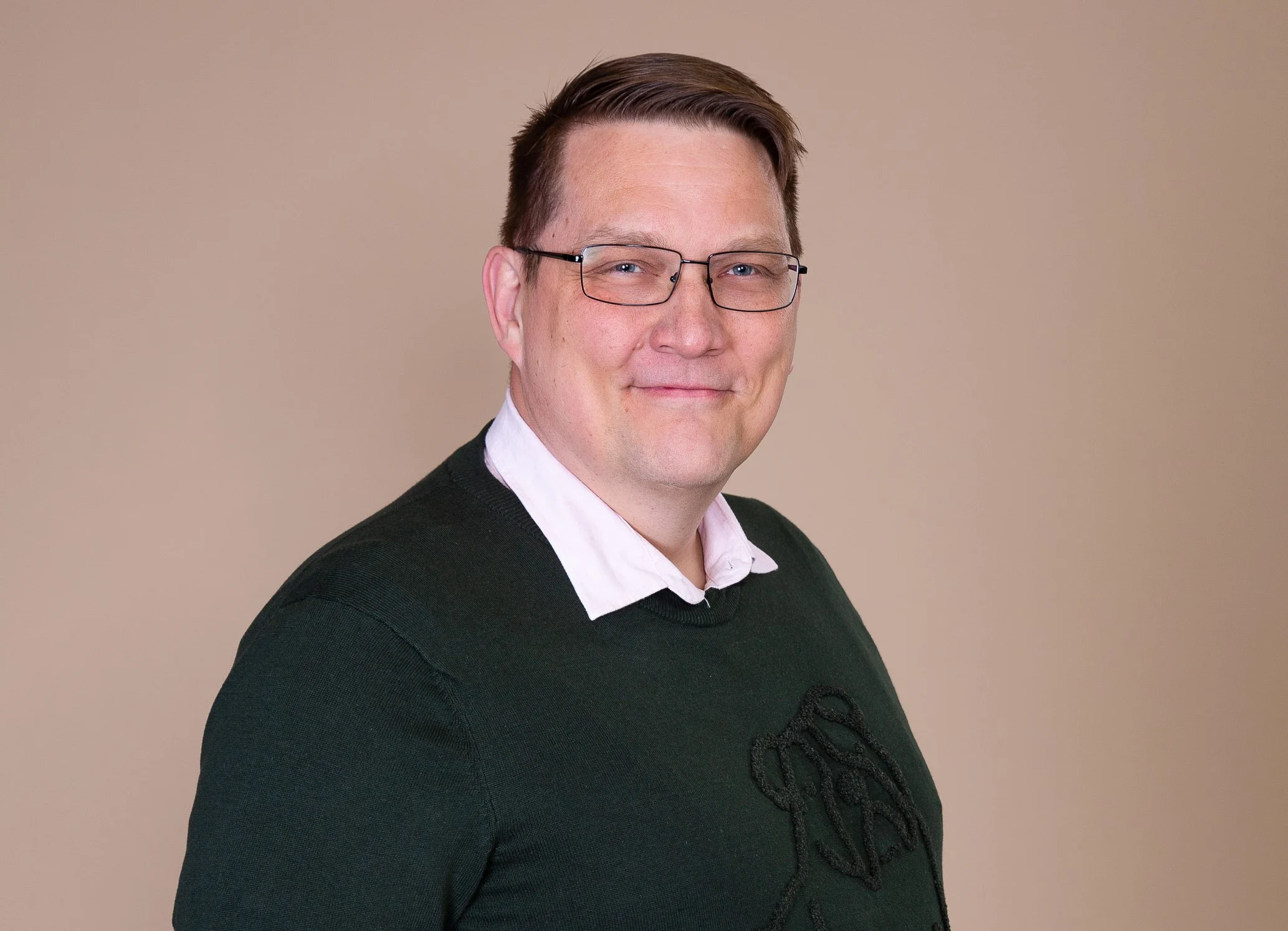 Marko Kolehmainen wearing glasses and a dark sweater against a light background