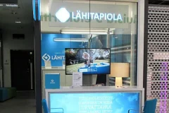 LähiTapiolan valaistu logo ja siniset ikkunateippaukset lasiseinäisessä toimipisteessä