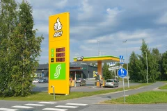 A yellow ABC fuel price pylon and green and yellow canopies beside the station entrance.