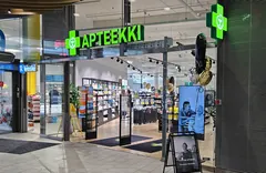 Vihreä Apteekki-valoteksti ja ristit Sanitum Apteekin lasisen sisäänkäynnin yläpuolella