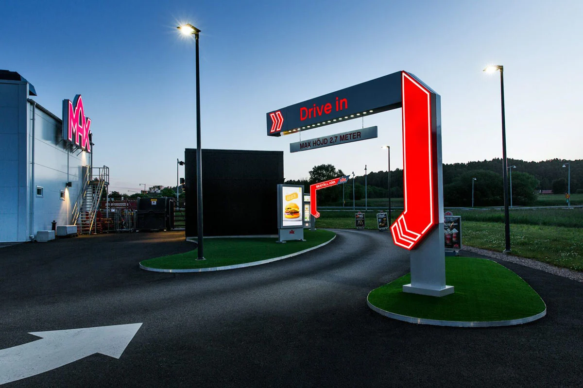 En rödvit Drive in-skylt med en stor belyst nedåtpil ovanför en körväg.