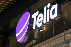 A purple Telia symbol and white illuminated letters above a store entrance.