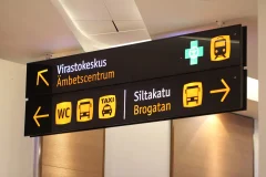 A Finnish and Swedish overhead sign directs visitors to the administrative centre, Siltakatu, toilets and transport services.