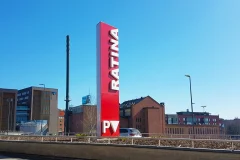 A red Ratina advertising tower rises among city buildings.