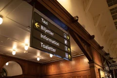 Katosta ripustettu opaste ohjaa takseille, lipunmyyntiin, neuvontaan ja wc-tiloihin.