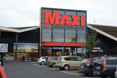 A red Maxi ICA Stormarknad sign on a store facade above parked cars.