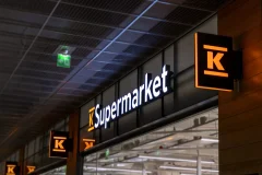 Illuminated K-Supermarket lettering and K logos above a store entrance.
