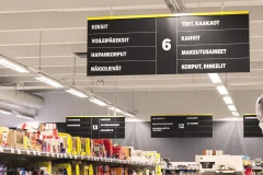 Black hanging product category signs above grocery store shelves.