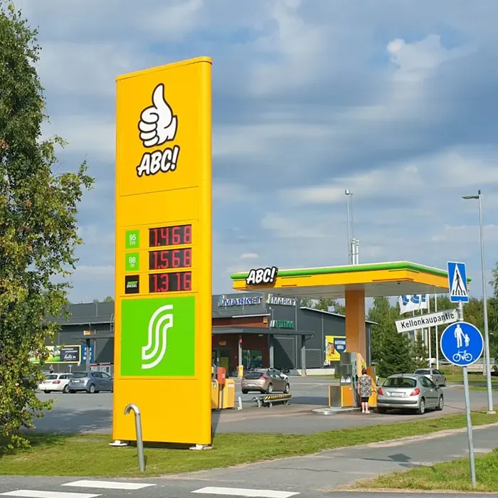 A yellow ABC fuel price pylon and filling station canopy beside a road.