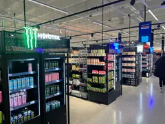 Valaistuja juomabrändien kylttejä KSM Löytiksen mustien juomahyllyjen yläpuolella