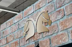 Two light-coloured horse-head shapes mounted on a brick-patterned surface Two light-coloured horse-head shapes mounted on a brick-patterned surface