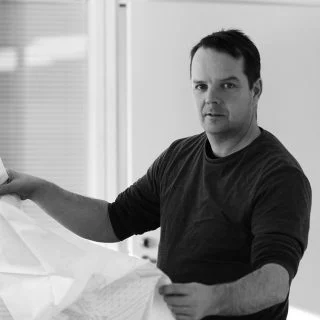 Eero Numminen holding a large white sheet in a black-and-white photograph.
