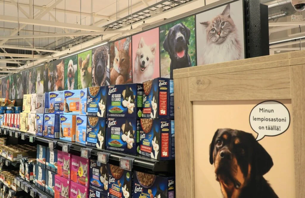 Kissojen ja koirien kuvat K-Supermarket Kauhavan eläinruokahyllyn yläpuolella