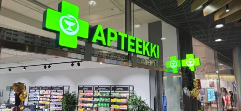 Green pharmacy lettering and cross logos above a glass storefront