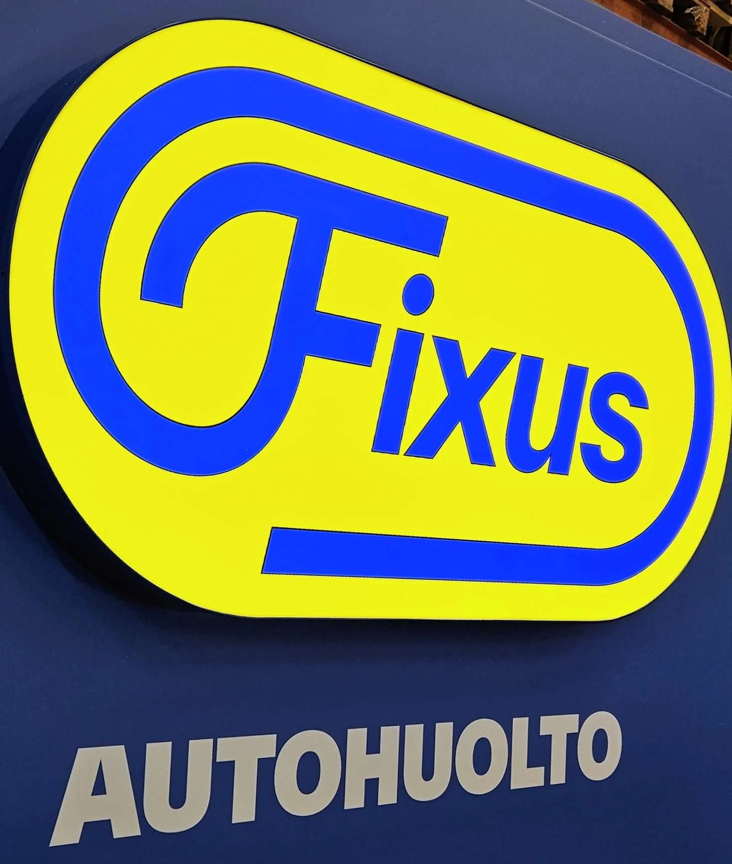 Fixus Autohuolto -logo sinikeltaisessa valomainoskotelossa