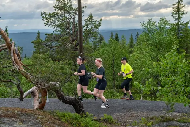 Imagonlaisia polkujuoksemassa metsäisessä vaaramaisemassa