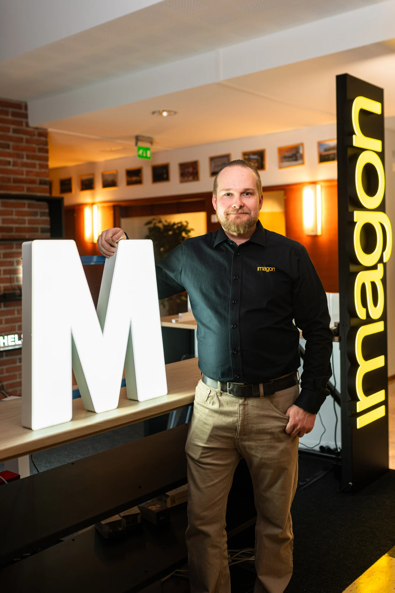 Mikko Okkonen suuren M-kirjaimen ja Imagon-kyltin vieressä