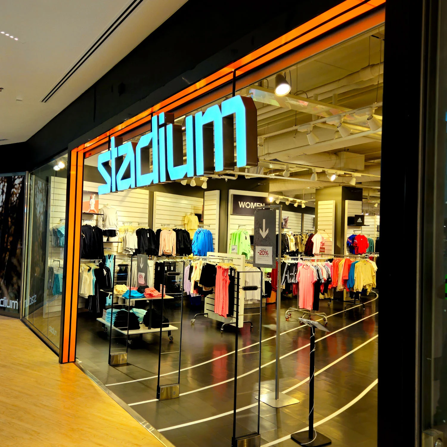 Stadiumin valokirjaimet ja oranssi kehys Itiksen myymälän sisäänkäynnillä