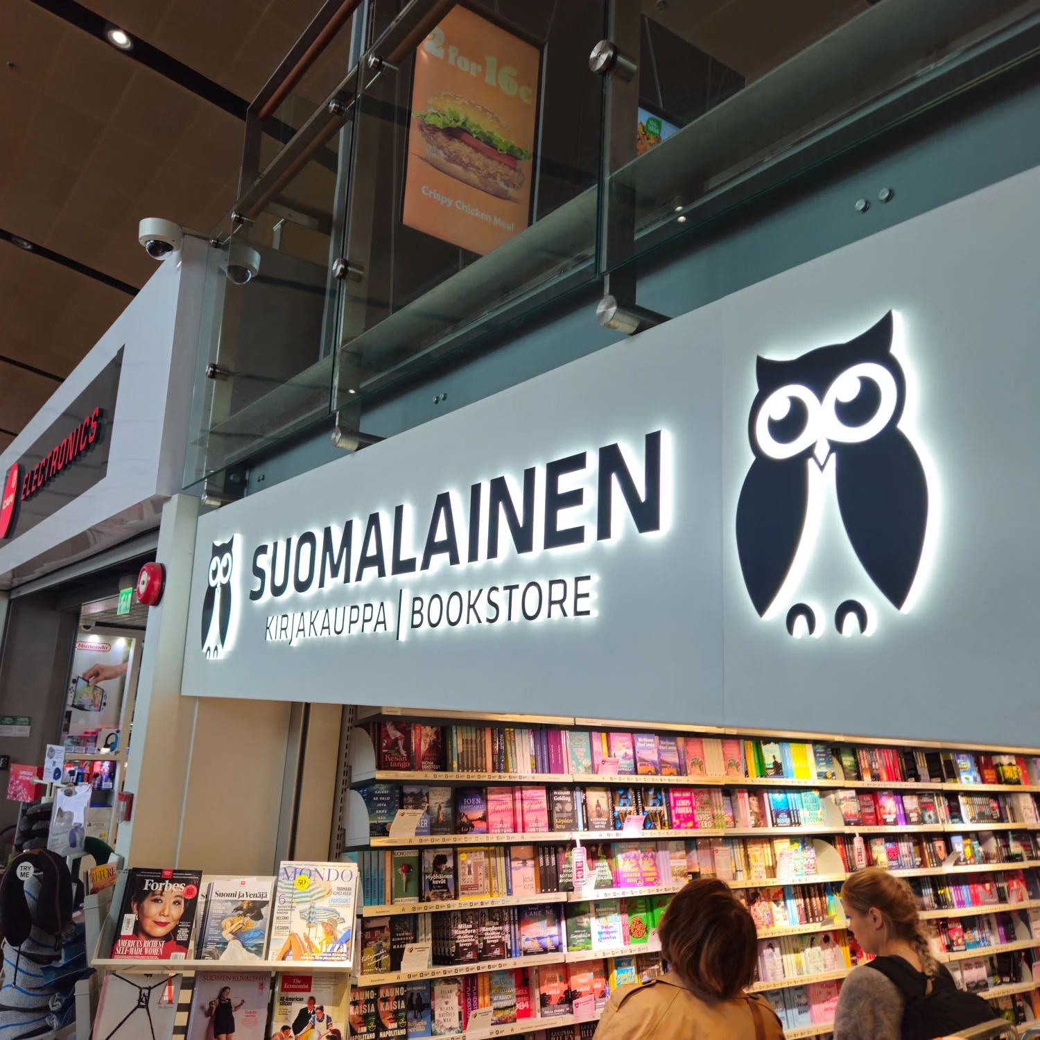 Valaistu Suomalainen Kirjakauppa -teksti ja pöllötunnus myymälän yllä