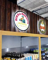 Pyöreät Birra Moretti- ja Lapin Kulta -kyltit juomahyllyn yläpuolella