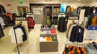 Sastan vaateosasto pöytineen, vaaterekkeineen ja tuotemerkkiopasteineen