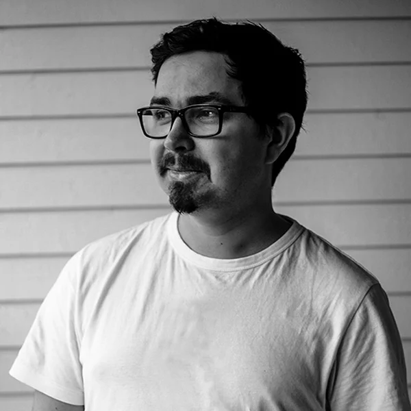 Black-and-white portrait of Nico wearing a light T-shirt and glasses.